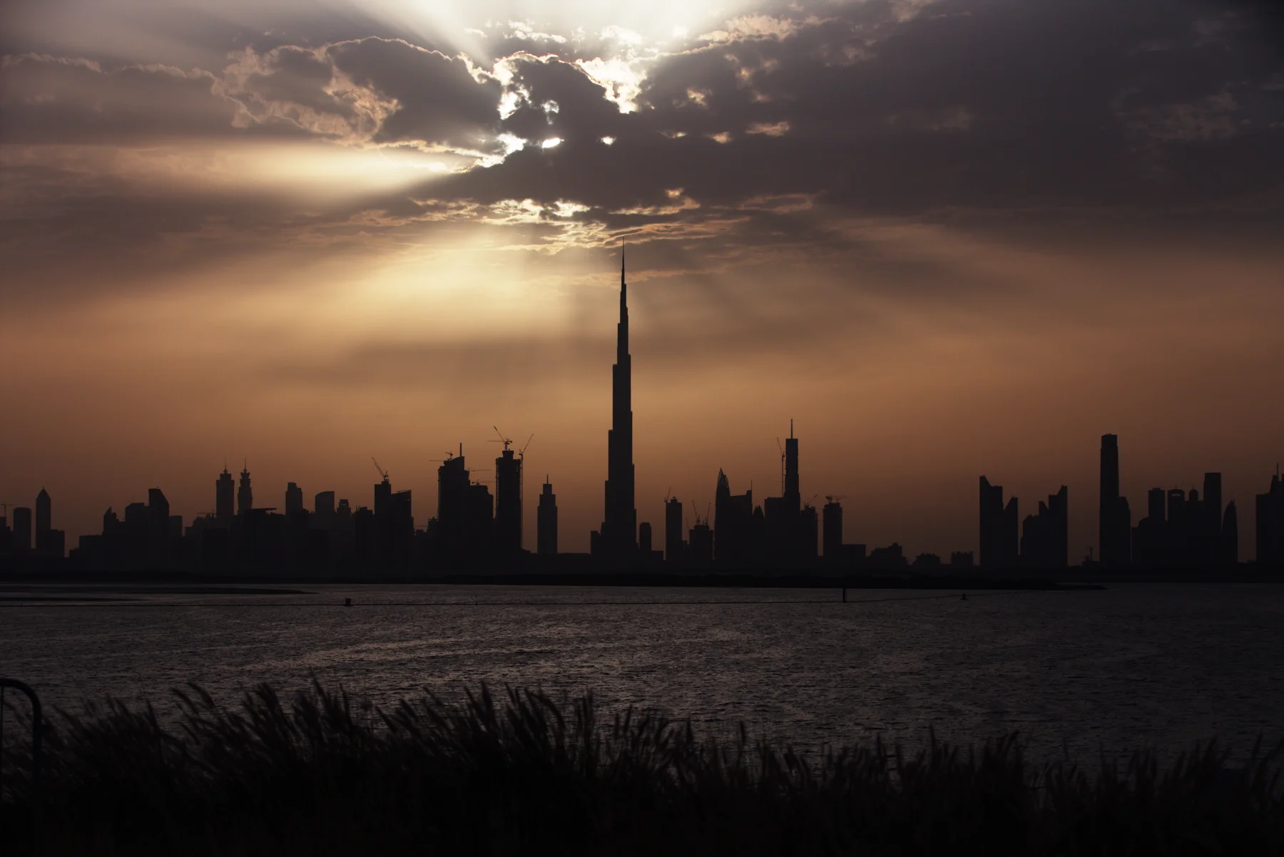 Burj Khalifa and the Dubai skyline at sunset across the water