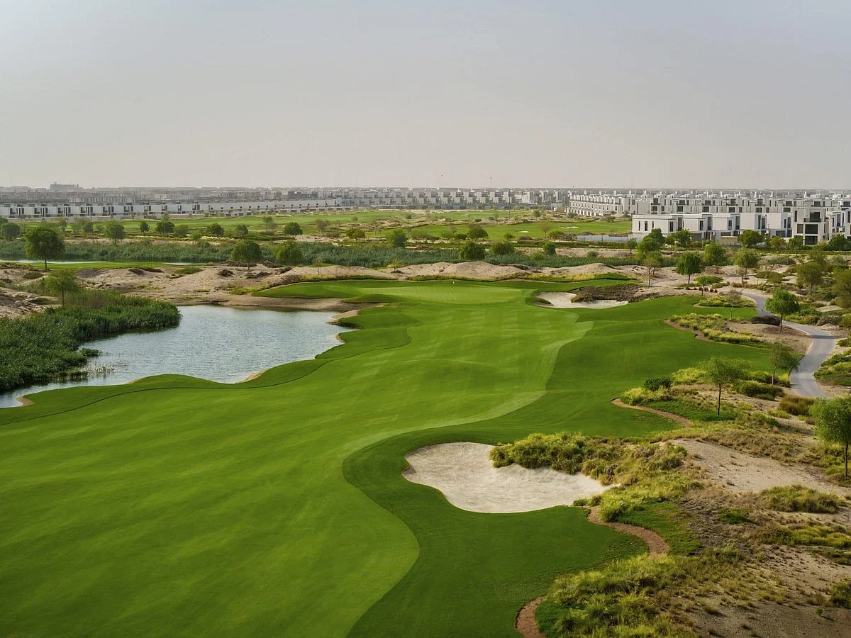 Emaar South Golf Club championship course with lake, bunkers and Emaar South townhouses in Dubai South